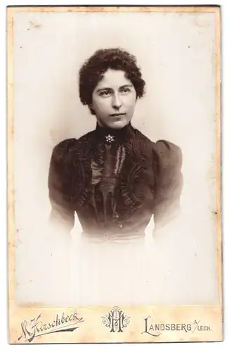 Fotografie M. Hirschbeck, Landsberg a. Lech, Junge Frau mit gelockten dunklen Haaren trägt ein besticktes Kleid
