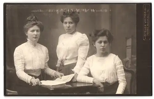 Fotografie Atelier Viktoria, Herne, Bahnhofstrasse 78, Portrait hübsch gekleidete Damen mit Zeitung am Tisch