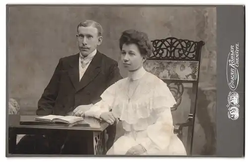 Fotografie Oskar Köhler, Chemnitz, Johannisplatz 16, Portrait junges Paar in hübscher Kleidung mit Buch