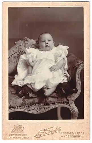 Fotografie A. & G. Taylor, Bradford, Portrait süsses Baby im weissen Kleid mit nackigen Füssen