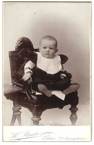 Fotografie H. Strube, Zittau i. S., Lessingstrasse 14, Kleinkind auf Stuhl mit Lätzchen