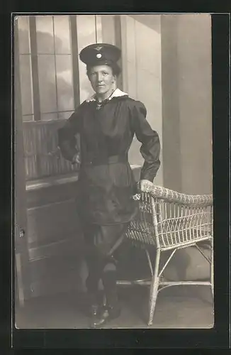 Foto-AK Eisenbahnerin in Dienstkleidung posiert an einem Korbstuhl