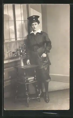 Foto-AK Eisenbahnerin in Dienstkleidung posiert an einem Tischchen