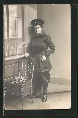 Foto-AK Eisenbahnerin in Dienstkleidung posiert an einem Stuhl