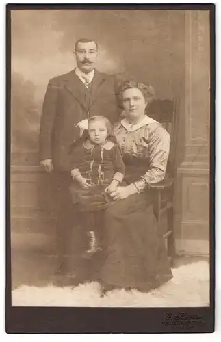 Fotografie E. Köster, Neustadt a/Rbge., Mittelstr., Mann mit Schnurrbart und Frau mit hochgekämmten Haaren und Mädchen