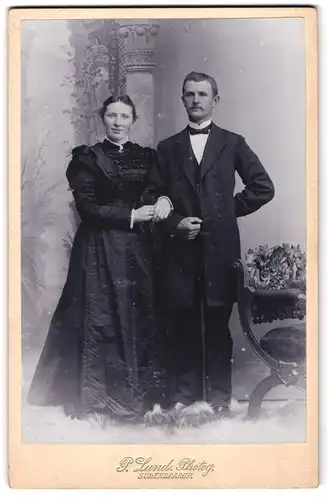 Fotografie P. Lund, Süderbrarup, Portrait bürgerliches Paar in modischer Kleidung