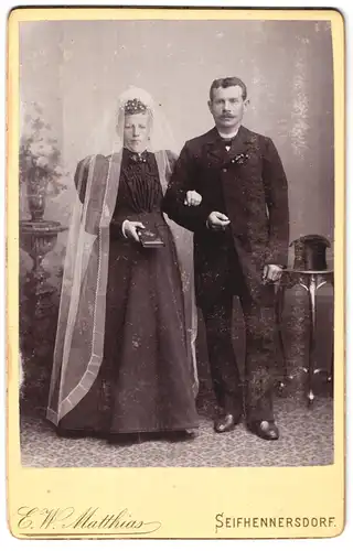 Fotografie E. W. Matthias, Seifhennersdorf, Portrait bürgerliches Paar in Hochzeitskleidung mit Schleier und Buch