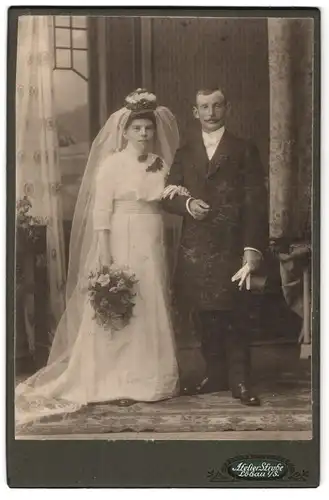 Fotografie Woldemar Strube, Löbau i /S., Portrait bürgerliches Paar in Hochzeitskleidung mit Schleier und Blumenstrauss
