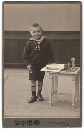 Fotografie Adolf Hartmann, Dessau, Portrait kleiner Junge im Matrosenanzug mit einem Buch