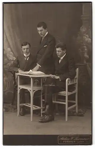 Fotografie Atelier Fernsner, Forbach i. Lothringen, Portrait drei charmante junge Männer an einem Tisch
