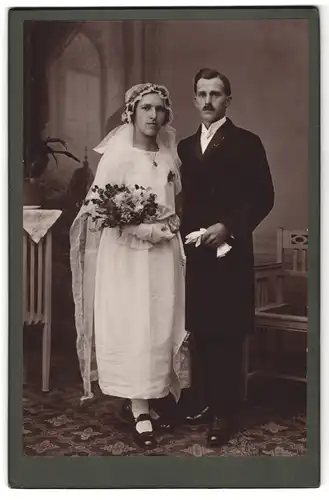 Fotografie unbekannter Fotograf und Ort, Portrait junges Paar in Hochzeitskleidung mit Schleier und Blumenstrauss