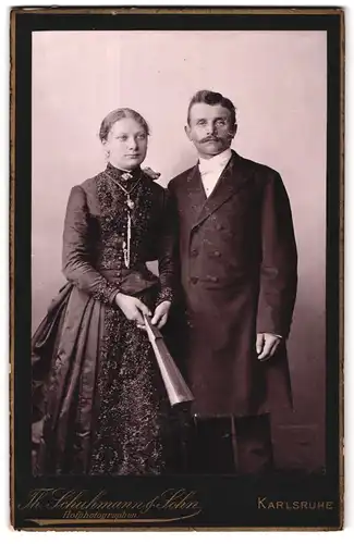 Fotografie Th. Schuhmann & Sohn, Karlsruhe, Amalienstrasse 57, Portrait junges Paar in hübscher Kleidung mit Fächer