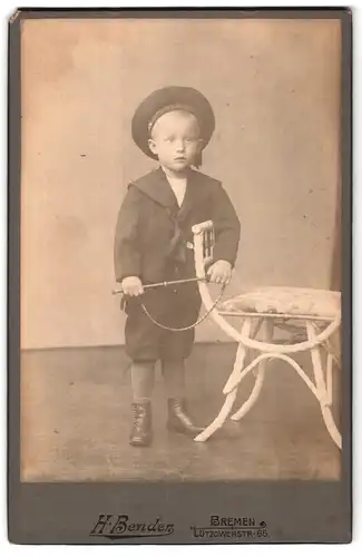 Fotografie H. Bender, Bremen, Lützowerstrasse 65, Portrait kleiner Junge im Matrosenanzug mit Mützenband und Peitsche