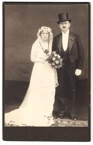 Fotografie H. Bauer, Trebbin, Portrait junges Paar in Hochzeitskleidung mit Schleier und Blumenstrauss