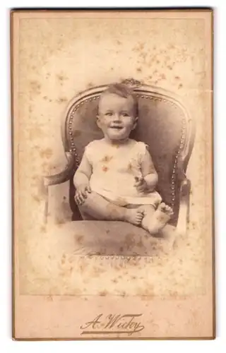 Fotografie A. Wicky, Berne-Soleure, Portrait lachender blonder Bube im Hemdchen auf einem Stuhl sitzend