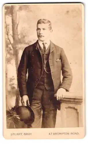 Fotografie W. & J. Stuart, London, 47 Brompton Road, Portrait charmanter junger Mann mit Hut im Anzug