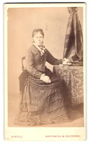 Fotografie Birtles, Northwich & Knutsford, Portrait sitzende Dame im eleganten Zweiteiler