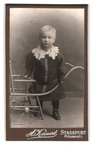 Fotografie A. Kleinert, Stassfurt, Prinzenstr., Portrait blonder Bube an einem Wagen stehend