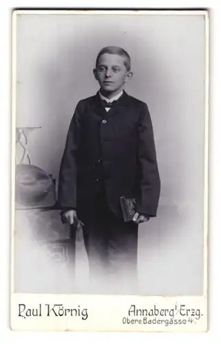 Fotografie Paul Körnig, Annaberg i / Erzg., Obere Badergasse 4, Portrait halbwüchsiger Knabe im Anzug mit Buch