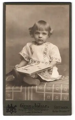 Fotografie Gebr. Noelle, Göttingen, Kurze-Strasse 5a, Süsses kleines Mädchen im Kleid mit Buch in der Hand