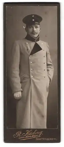 Fotografie R. Käding, Senftenberg N./L., Portrait Soldat Rudolf Görsdorf im Mantel mit Uniformmütze