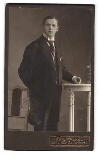Fotografie Karl Mäckel, Burgstädt / Sachsen, Böhmestr. 2, Junger Mann im Anzug neben einem Beistelltisch