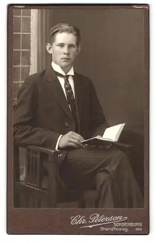 Fotografie Chr. Petersen, Sonderburg, Brandtsweg, Junger Mann im Anzug mit Buch und gekämmten Haaren