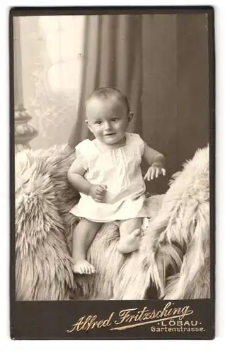 Fotografie Alfred Fritzsching, Löbau, Gartenstrasse, Portrait süsses Kleinkind im weissen Hemd mit nackigen Füssen
