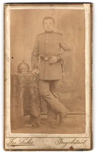 Fotografie Jos. Luber, Ingolstadt, Proviantgasse 878, Portrait bayr. Soldat der Infanterie, Pickelhaube auf dem Tisch