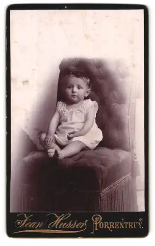 Fotografie Jean Husser, Porrentruy, Kleines Kind im weissen Hemd auf einem Sessel