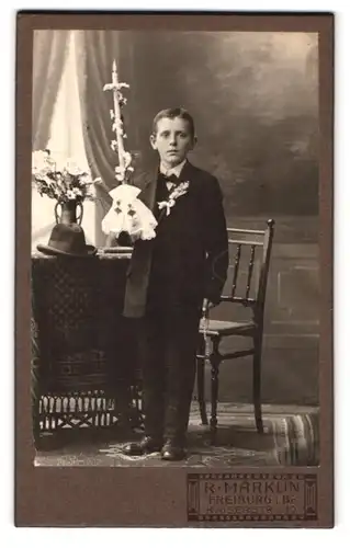 Fotografie R. Märklin, Freiburg i. B., Kaiserstr. 10, Portrait junger Knabe im Anzug mit Kerze, Kommunion
