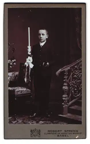 Fotografie Robert Spreng, Basel, Clarastr. 54, Portrait junger Knabe im Anzug mit Kerze und Bibel, Kommunion