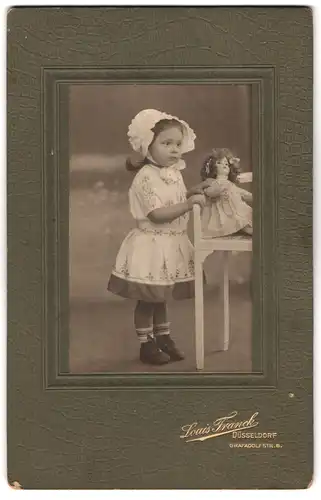 Fotografie Louis Franck, Düsseldorf, Graf-Adolf-Str. 6, Portrait niedliches Mädchen mit Häubchen und Puppe