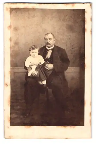 Fotografie unbekannter Fotograf und Ort, Portrait bürgerlicher Herr mit Kleinkind auf dem Schoss