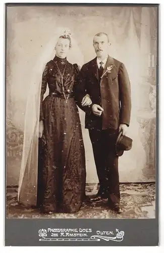 Fotografie A. Amstein, Olten, Portrait Brautpaar im schwarzen Kleid mit Schleier und Hut