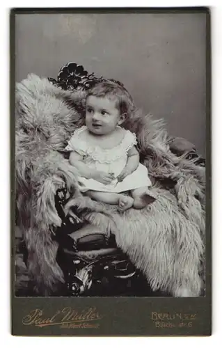 Fotografie Paul Müller, Berlin, Blücherstr. 6, Kleines Kind im weissen Hemd sitzend auf einem Fell