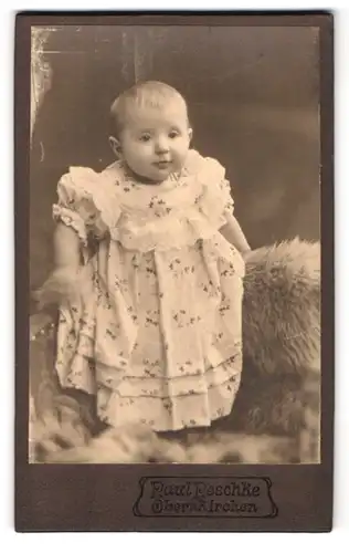 Fotografie Paul Peschke, Obernkirchen, Kleines Kind im Kleid stehend auf einem Fell