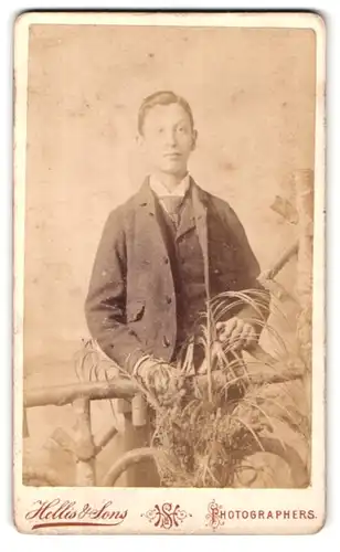 Fotografie Hellis & Sons, London, 211 & 213 Regent St., Portrait niedlicher Bube im Anzug am Holzgeländer stehend