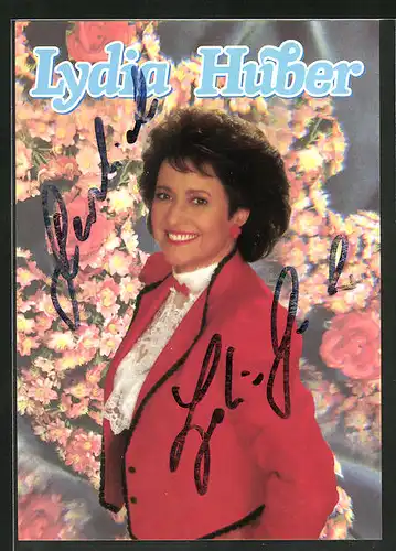 AK Musikerin Lydia Huber in rotem Blazer vor einem Blumenstrauch stehend, Autograph