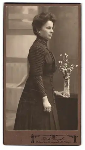 Fotografie Rich. Vogel, Glauchau, Leipzigerstr. 70, Dame im Kleid von der Seite mit einer Blume in der Vase
