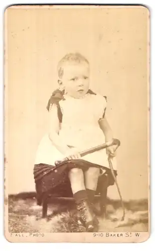Fotografie T. Fall, London-W, 9-10 Baker Street, Portman Square, Portrait kleines Mädchen im Kleid mit Peitsche