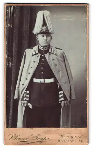 Fotografie Bruno Grupe, Berlin, Blücherstr. 56, Portrait preussischer Gardesoldat im Mantel, Pickelhaube mit Paradebusch