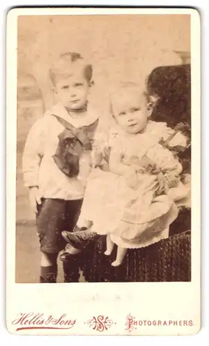 Fotografie Hellis & Sons, London-W, 211 & 213, Regent Street, Portrait hübsch gekleidetes Kinderpaar mit Puppe