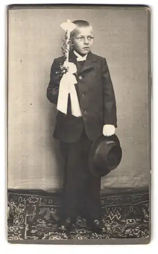 Fotografie unbekannter Fotograf und Ort, Portrait Knabe im schwarzen Anzug mit Kommunionskerze