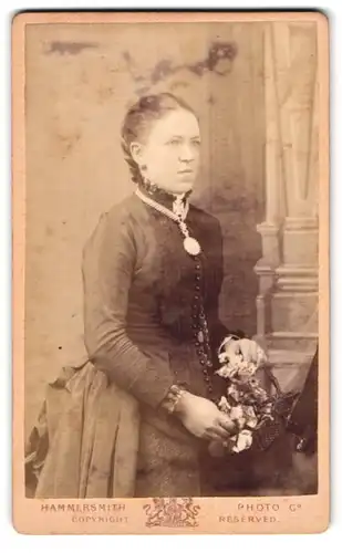 Fotografie Hammersmith, London, 31 King St. West, Frau mit Sonnenamulett mit Blumenstrauss