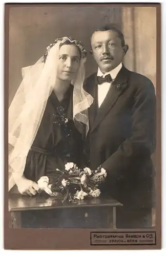 Fotografie Samson & Cie, Zürich, Hochzeitspaar in schwarz gekleidet, Braut mit Blumenstrauss & Schleier