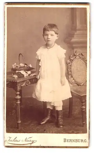 Fotografie Julius Nary, Bernburg, Carlsplatz 29, Portrait niedliches kleines Mädchen mit Blumenkorb am Tisch stehend