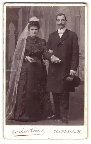 Fotografie Gustav Krenz, Schirgiswalde, Portrait Brautpaar in Schwarz gekleidet mit Schleier und Zylinder