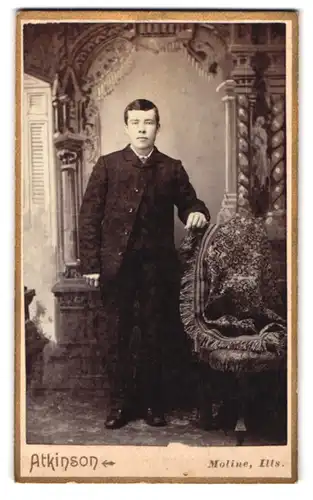 Fotografie Atkinson, Moline, Portrait junger Mann im Anzug vor einer Studiokulisse