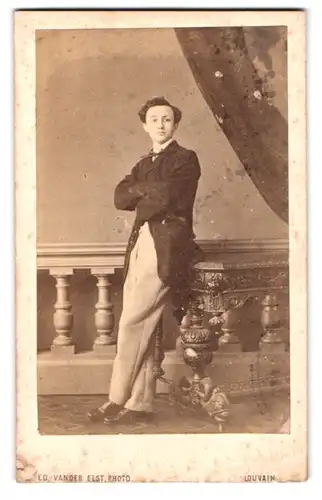 Fotografie Edouard vander Elst, Louvain, Rue Tirlemont 65, Portrait junger Mann im Anzug lehnt an einem Tisch